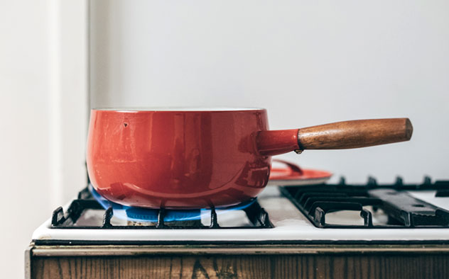 A saucepan over a stove using green gas
